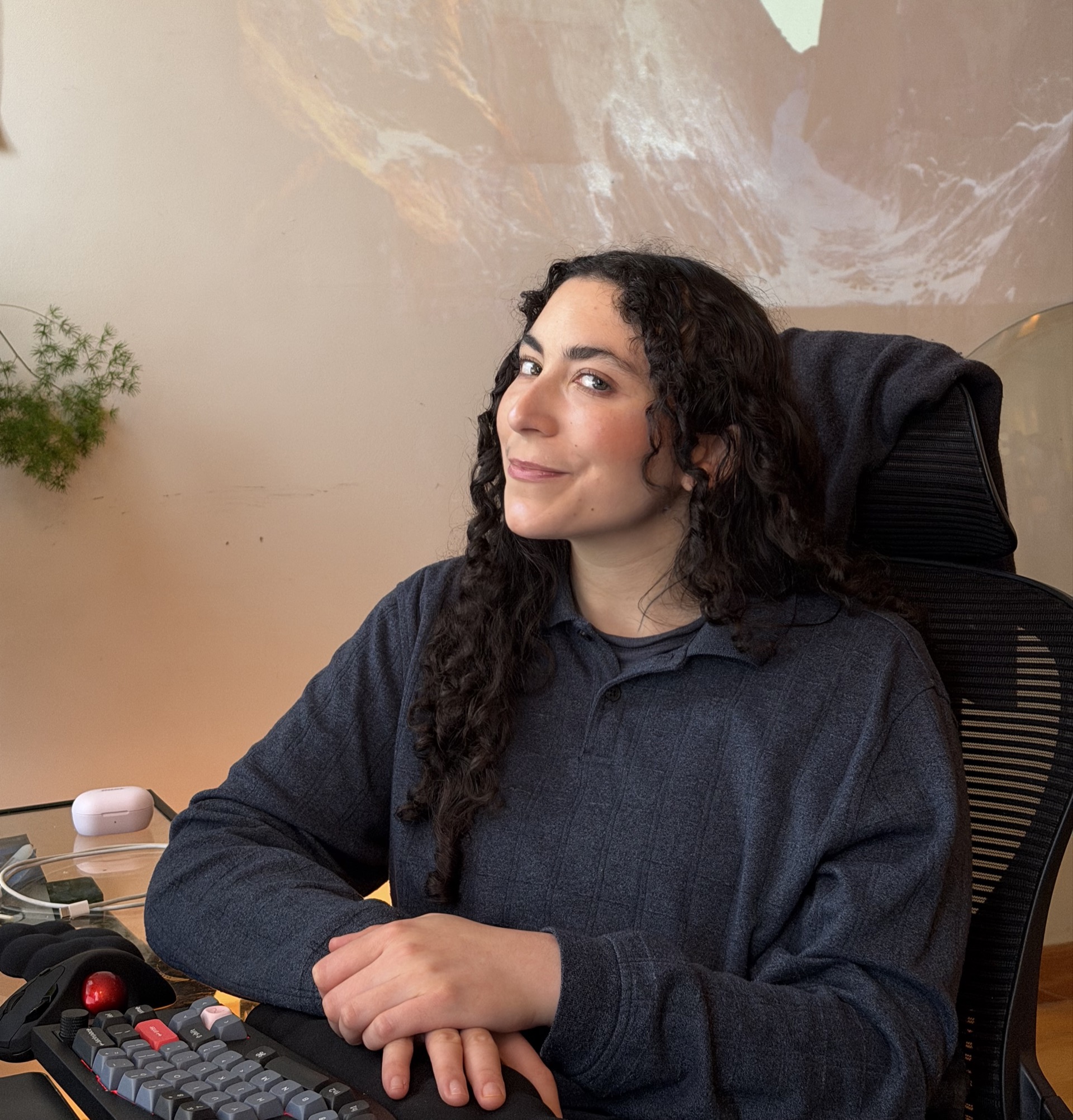 Lines sitting at desk with an ergonomic split keyboard and mountain projection on the wall