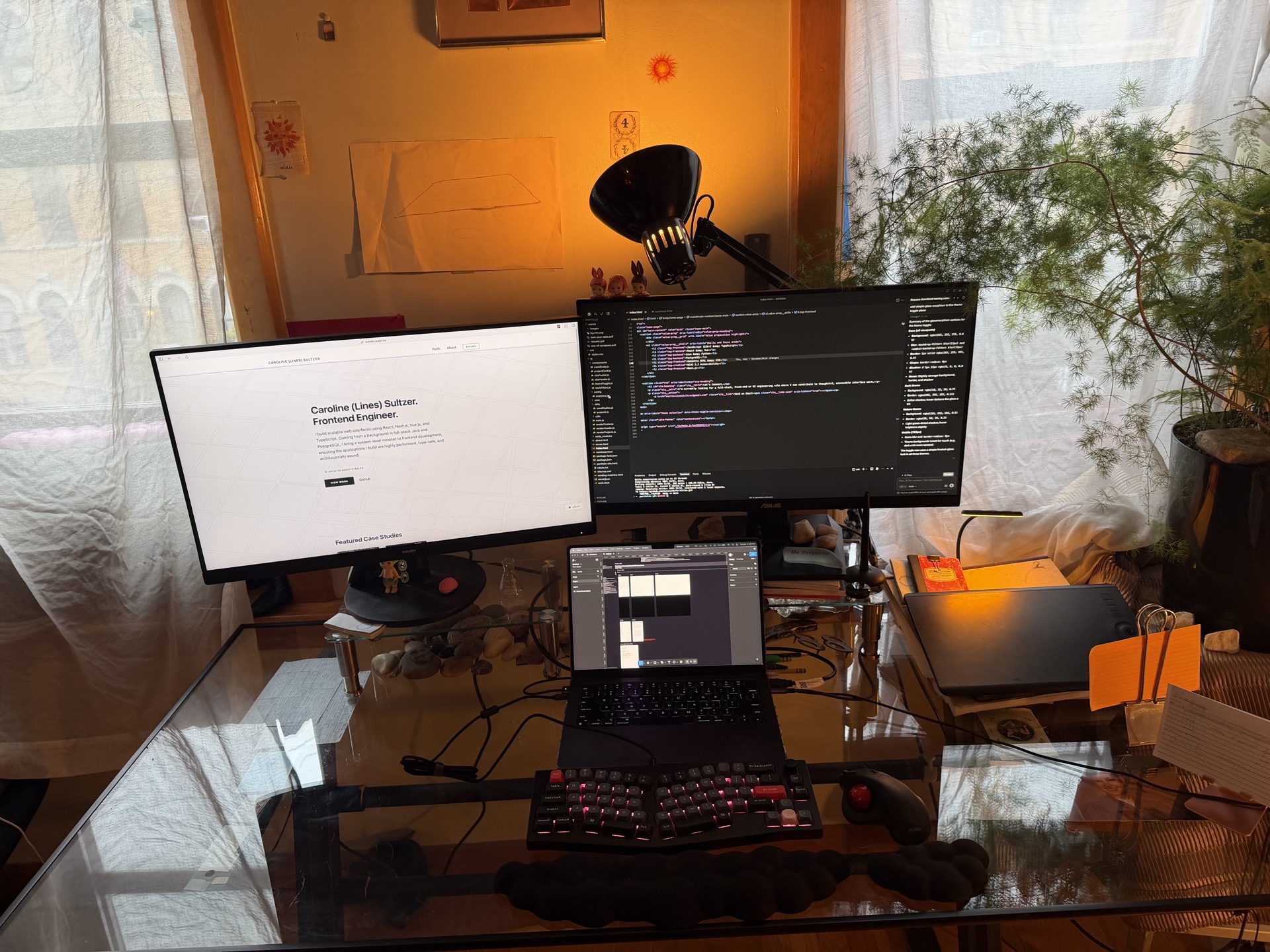 Remote workspace setup with dual monitors, laptop, drawing tablet, and code editor open